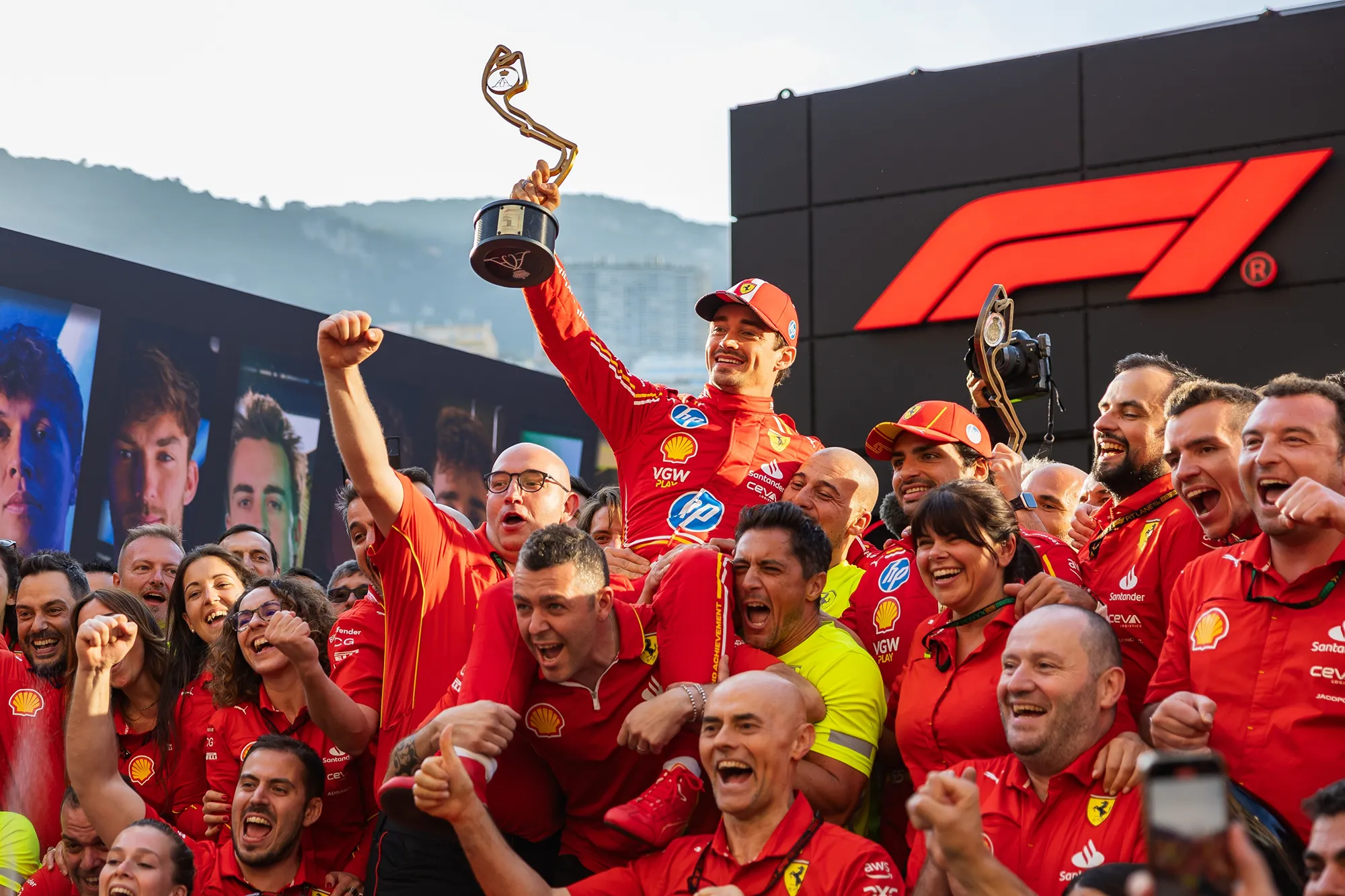 Ferrari's F1 team joyfully celebrates their victory, holding the trophy aloft amidst cheers and confetti.