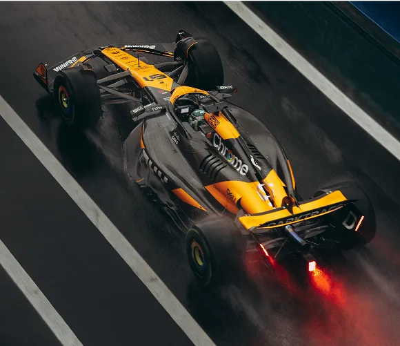 A yellow and black racing car speeds along a wet track, showcasing its dynamic design and performance capabilities.