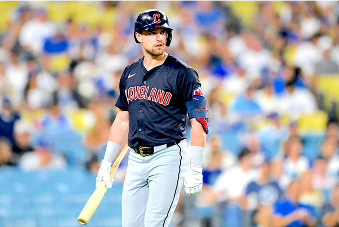 A baseball player stands on the field, holding a bat, ready to swing during a game.