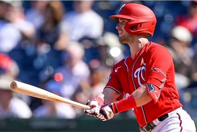 A baseball player in red swings a bat, poised for action on the field