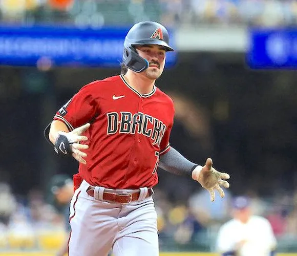 A baseball player in a red uniform sprinting towards first base during a game.