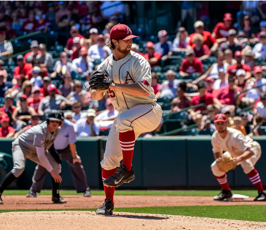 A baseball player in a red and white uniform is in the act of pitching a ball on the field.