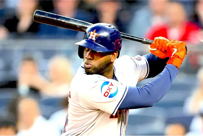 A baseball player stands poised with a bat, ready to swing, showcasing athleticism and focus on the field.