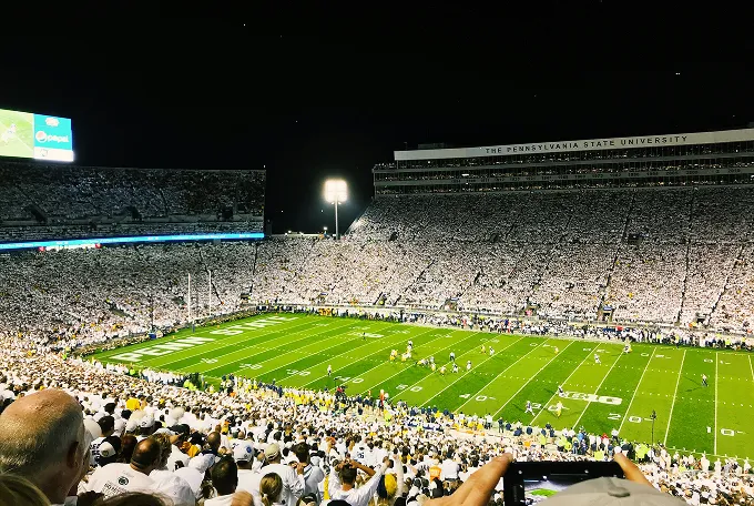 A large crowd of spectators intently watching a football game, filled with excitement and anticipation.